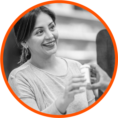 Photo of a smiling woman at a pharmacy being handed a prescription